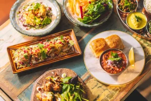 Små retter på et tre bord. Streetfood. Farger. Ulike retter. Brød og saus på et marble fat. Dhai puri. Samosa chaat. Thali. Korriander. Chili wada.